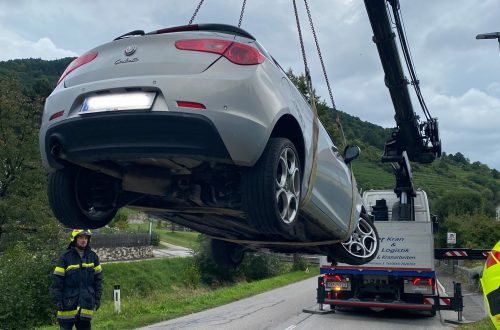 PKW der von Kran hochgehoben wird.